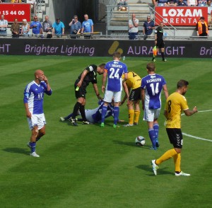 Lars tilser en skadet Lyngby-spiller, inden han skal give en advarsel til en Fredericia-spiller